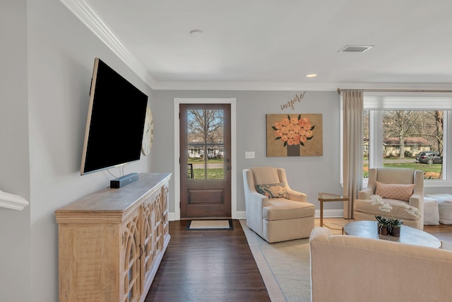 living area with dark wood-type flooring, visible vents, crown molding, and baseboards