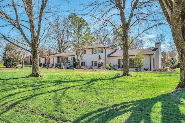rear view of house with stucco siding and a yard