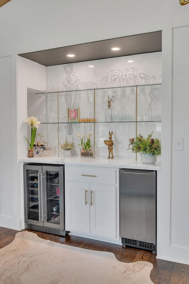 bar featuring dark wood finished floors, a dry bar, refrigerator, and wine cooler