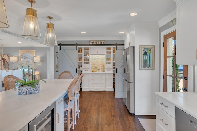 kitchen featuring a barn door, appliances with stainless steel finishes, white cabinets, and light countertops
