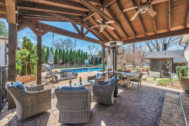 view of patio featuring outdoor dining area, a sunroom, an outdoor pool, and a ceiling fan