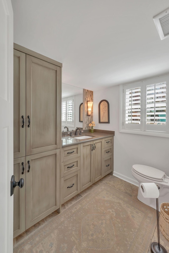 bathroom featuring toilet, vanity, and baseboards