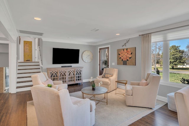 living area with wood finished floors, visible vents, baseboards, and ornamental molding