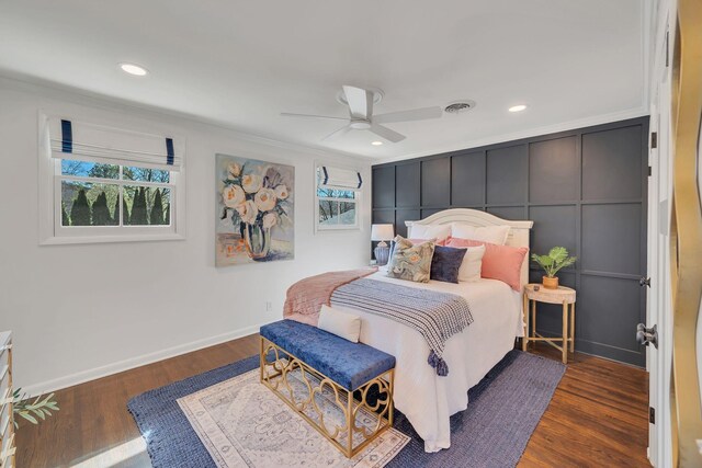 bedroom with wood finished floors, visible vents, baseboards, and ornamental molding