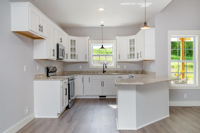 kitchen featuring glass insert cabinets, appliances with stainless steel finishes, plenty of natural light, and a peninsula