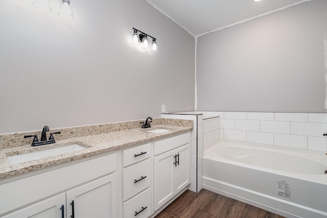 full bathroom featuring double vanity, a sink, a bath, and wood finished floors
