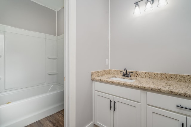 full bath featuring vanity, washtub / shower combination, and wood finished floors
