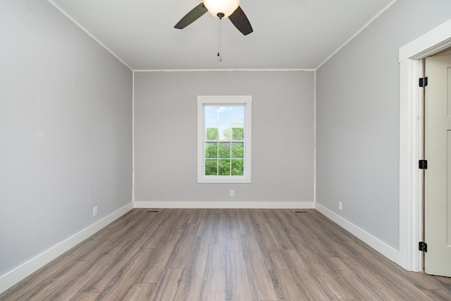 empty room with a ceiling fan, baseboards, ornamental molding, and wood finished floors