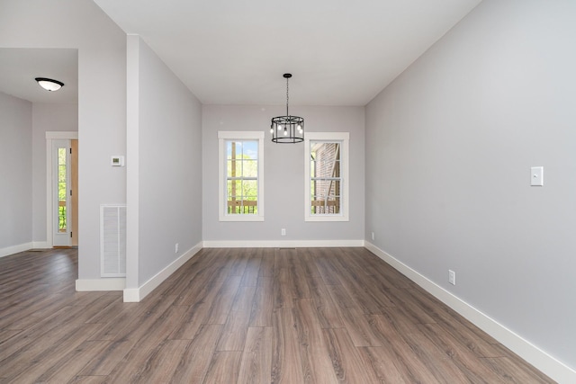 unfurnished dining area with visible vents, dark wood-type flooring, a chandelier, and a wealth of natural light