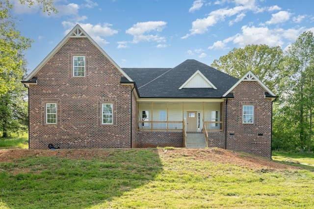 view of front of home with covered porch, a front lawn, and brick siding