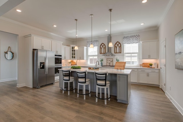 kitchen with white cabinets, wall chimney exhaust hood, decorative backsplash, and stainless steel appliances