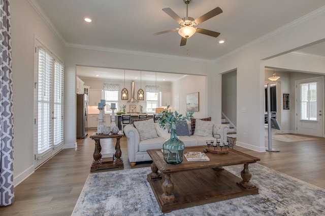 living area with baseboards, a ceiling fan, stairs, and light wood-style flooring
