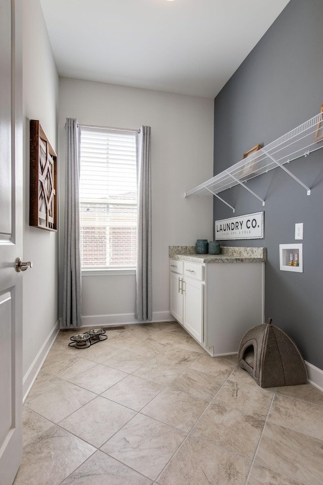 clothes washing area with baseboards, cabinet space, hookup for a washing machine, and light tile patterned floors