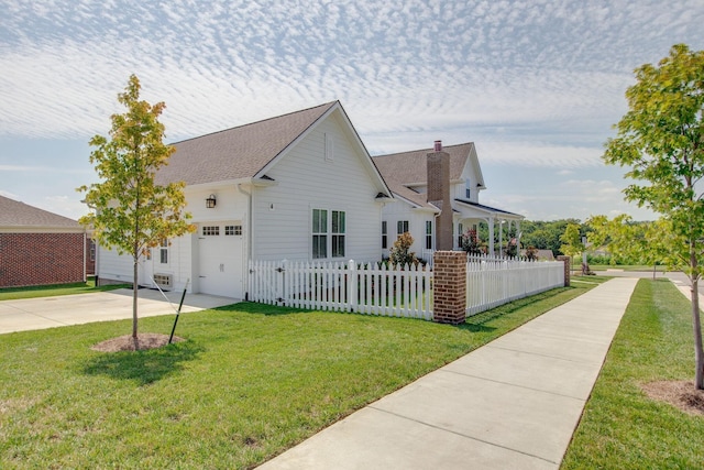 view of front facade featuring a chimney, concrete driveway, fence private yard, a front yard, and a garage