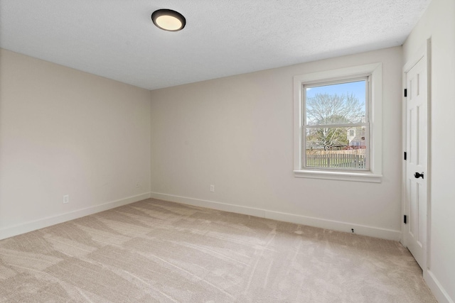 unfurnished room with light colored carpet, baseboards, and a textured ceiling
