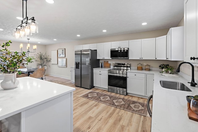 kitchen with recessed lighting, stainless steel appliances, light countertops, a sink, and light wood-style flooring