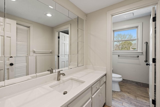 bathroom featuring recessed lighting, wood finished floors, toilet, and vanity