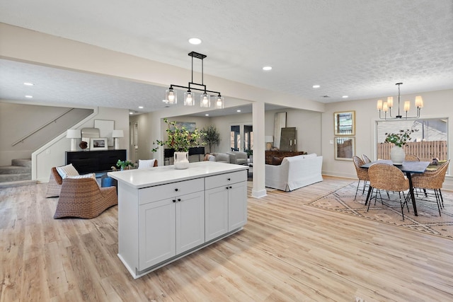 kitchen featuring an inviting chandelier, decorative light fixtures, a center island, light wood-style flooring, and open floor plan