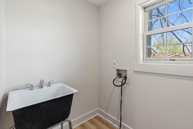 clothes washing area featuring baseboards, light wood finished floors, laundry area, and washer hookup