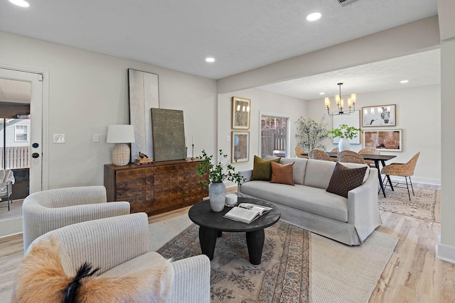 living area featuring light wood-style flooring, baseboards, recessed lighting, and a notable chandelier
