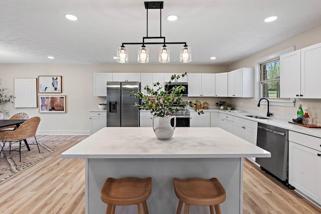 kitchen featuring white cabinetry, appliances with stainless steel finishes, a sink, and a breakfast bar