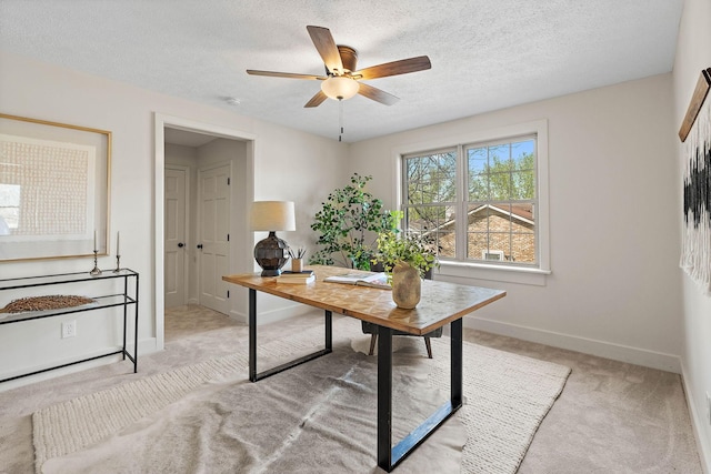 office area with a textured ceiling, a ceiling fan, baseboards, and light carpet
