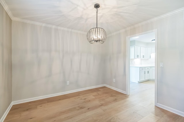 unfurnished dining area with ornamental molding, baseboards, a notable chandelier, and light wood finished floors