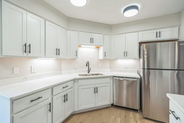 kitchen with white cabinets, light wood-style flooring, stainless steel appliances, and a sink