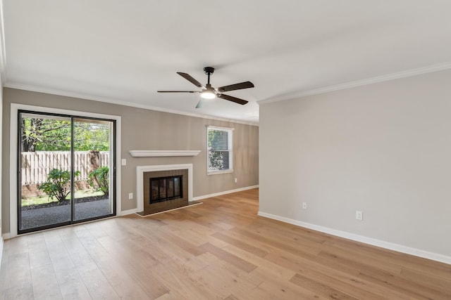unfurnished living room featuring light wood finished floors, a ceiling fan, ornamental molding, baseboards, and a glass covered fireplace