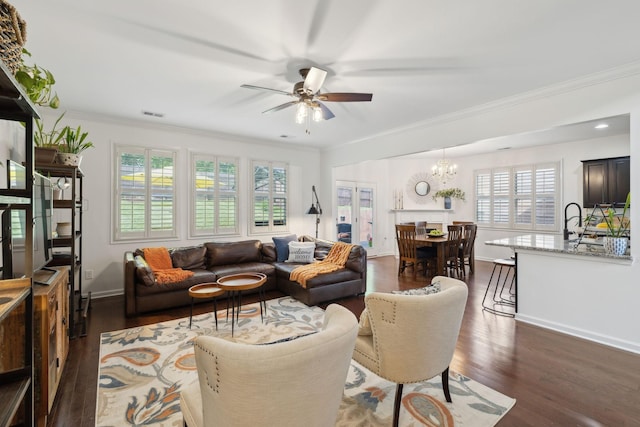 living area with ceiling fan, ornamental molding, dark wood-type flooring, a chandelier, and baseboards