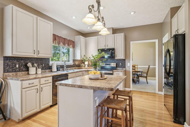 313 Walpole Ct, Nolensville, TN 37135 - kitchen featuring light wood-style flooring, a kitchen breakfast bar, a sink, and black appliances