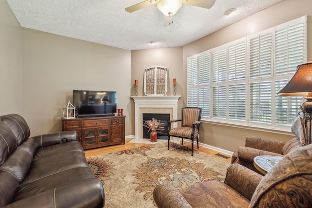313 Walpole Ct, Nolensville, TN 37135 - living room featuring a fireplace with flush hearth, a textured ceiling, visible vents, wood finished floors, and ceiling fan