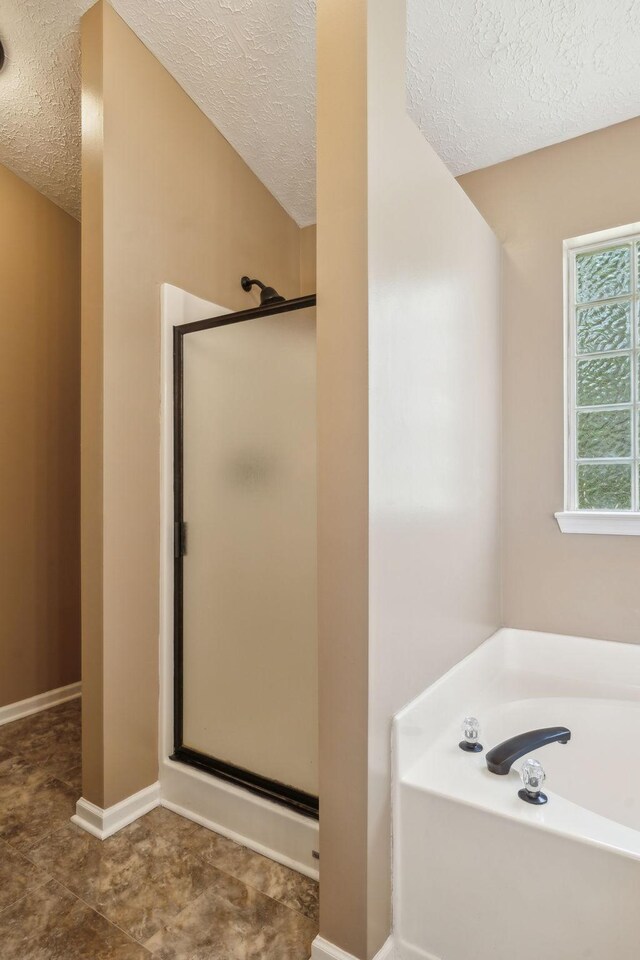 313 Walpole Ct, Nolensville, TN 37135 - bathroom featuring a shower stall, a textured ceiling, a garden tub, and baseboards