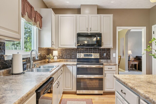 313 Walpole Ct, Nolensville, TN 37135 - kitchen featuring light wood-style flooring, a sink, decorative backsplash, light countertops, and black appliances