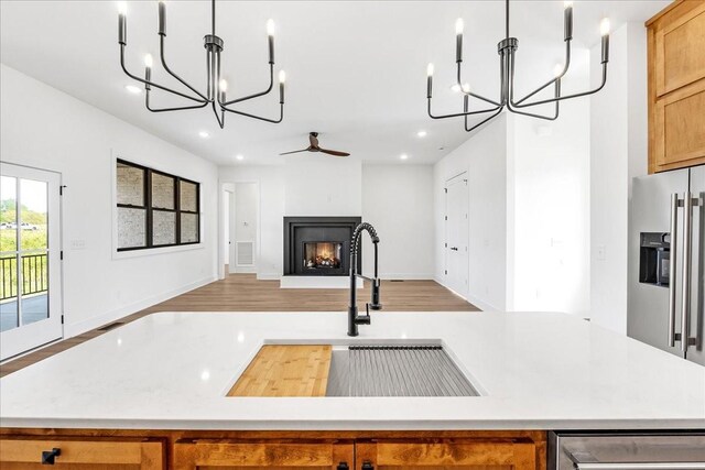 kitchen featuring high end refrigerator, recessed lighting, a warm lit fireplace, and light countertops