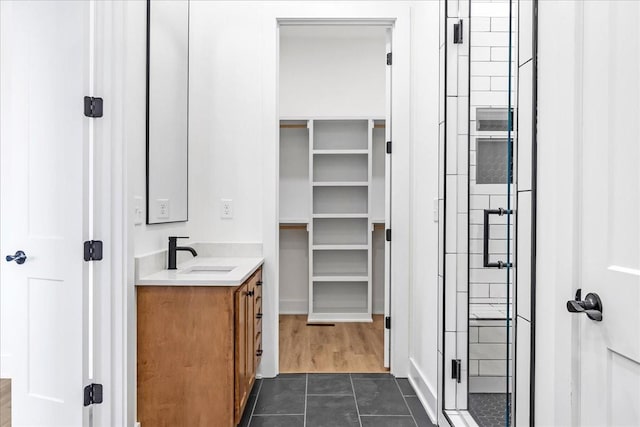 bathroom featuring tile patterned floors, vanity, a spacious closet, and a stall shower