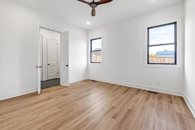spare room featuring visible vents, light wood finished floors, baseboards, and ceiling fan