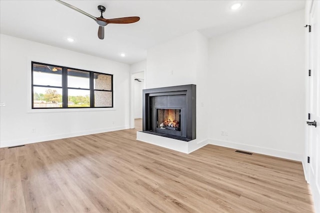 unfurnished living room featuring light wood finished floors, baseboards, recessed lighting, a ceiling fan, and a multi sided fireplace