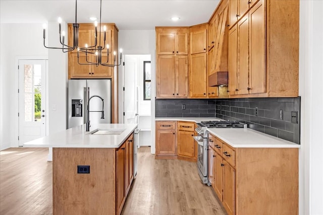 kitchen featuring a chandelier, stainless steel appliances, light wood finished floors, and a sink