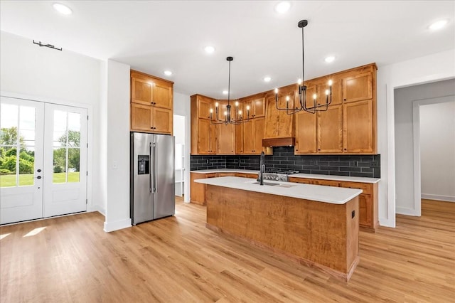 kitchen with a notable chandelier, stainless steel appliances, light countertops, and light wood-style flooring
