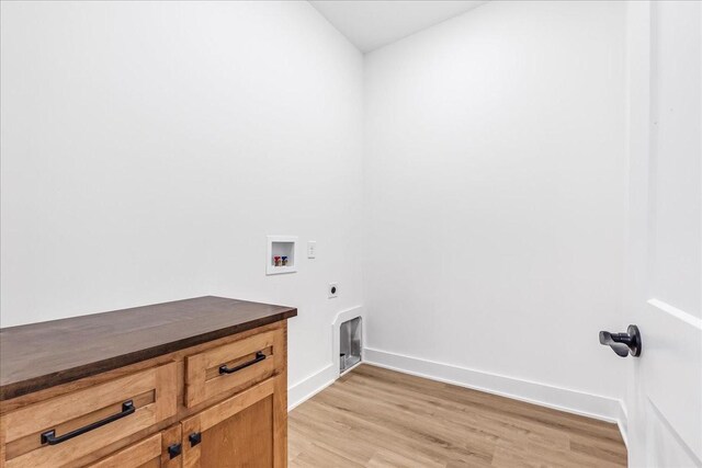 washroom featuring hookup for an electric dryer, light wood-style floors, hookup for a washing machine, baseboards, and cabinet space