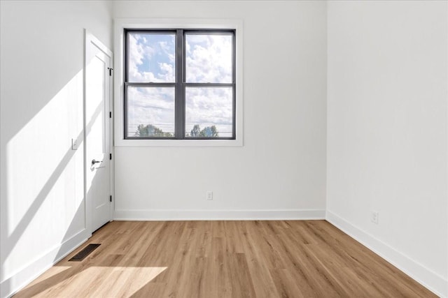 empty room featuring light wood-style floors, visible vents, and baseboards
