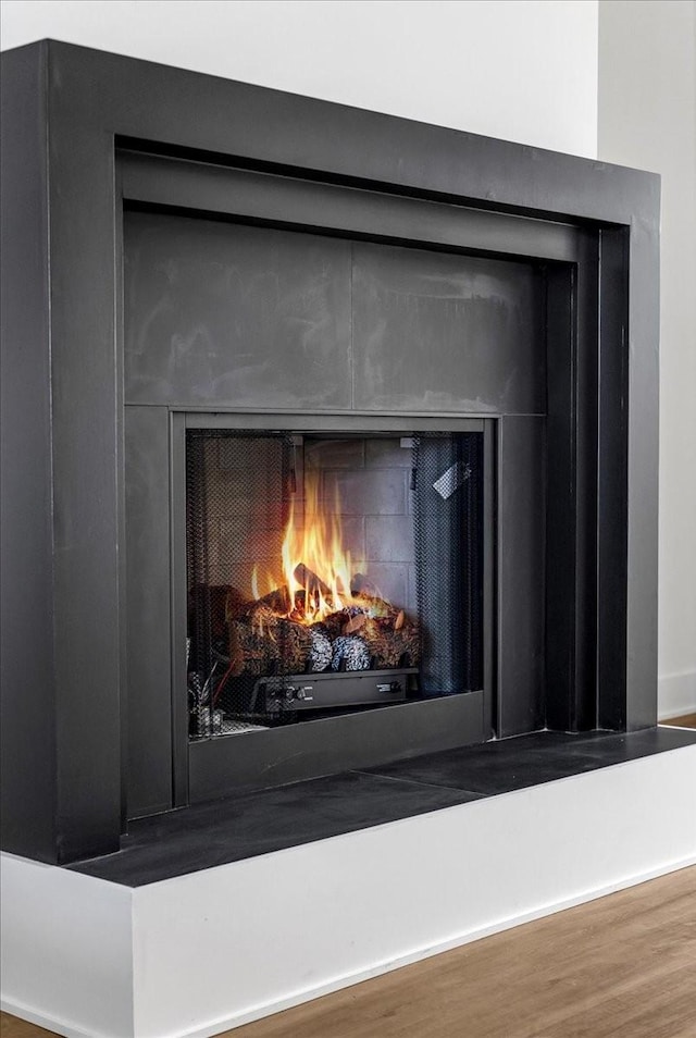 room details featuring a warm lit fireplace and wood finished floors
