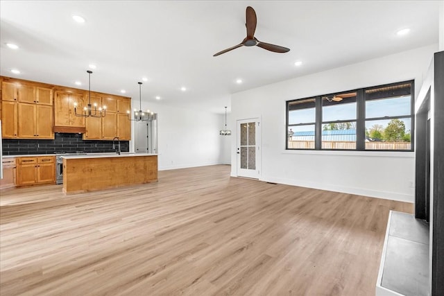 interior space featuring ceiling fan with notable chandelier, baseboards, recessed lighting, and light wood-style floors