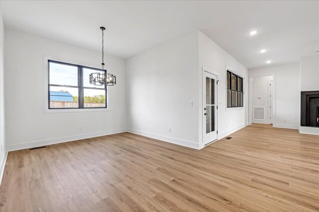 unfurnished dining area with light wood finished floors, baseboards, visible vents, and a chandelier