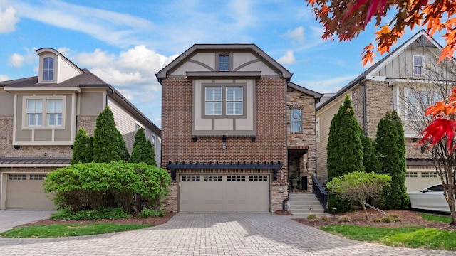 view of front of home with an attached garage, brick siding, decorative driveway, and stone siding
