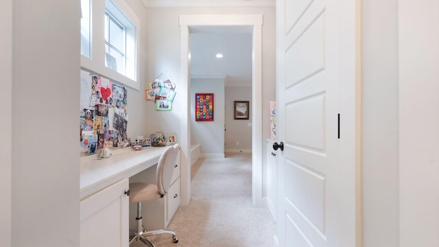 hallway with light colored carpet, baseboards, and ornamental molding