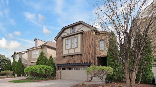 view of front of home with stucco siding, driveway, brick siding, and a garage