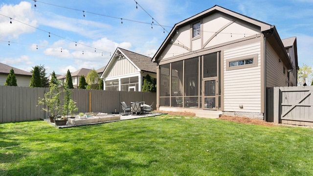 rear view of house featuring a yard, a patio area, a sunroom, and a fenced backyard