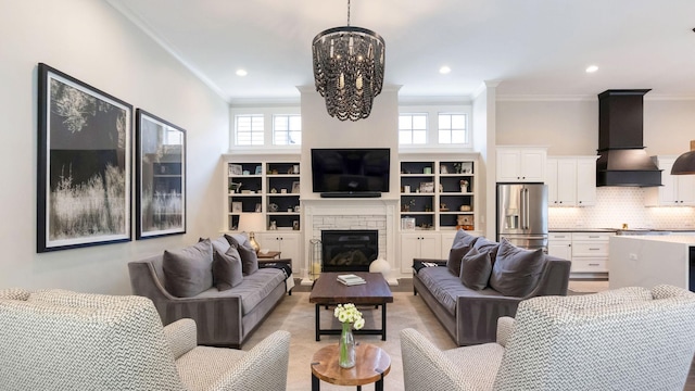 living room featuring plenty of natural light, a notable chandelier, a stone fireplace, and ornamental molding